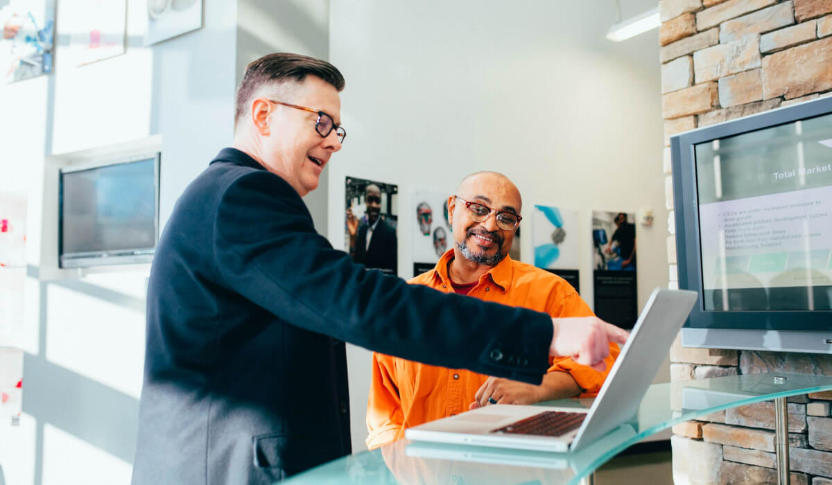 Peer-to-Peer-Lernen im Unternehmen: Kollegin unterrichtet Kollegen am Laptop