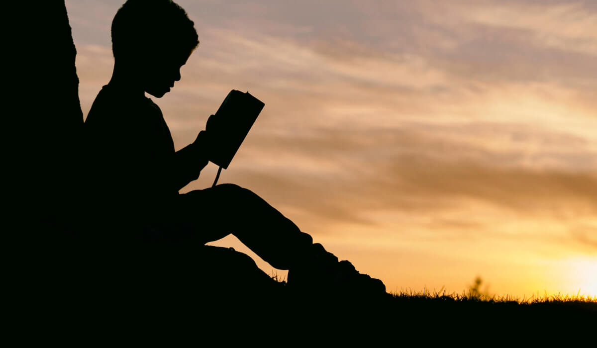 Kind liest ein Buch vor Sonnenuntergang als Symbol für effektives Lernen