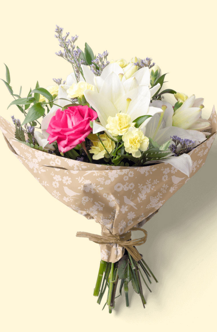 A bouquet of flowers wrapped in kraft wax tissue paper with flowers printed in white ink