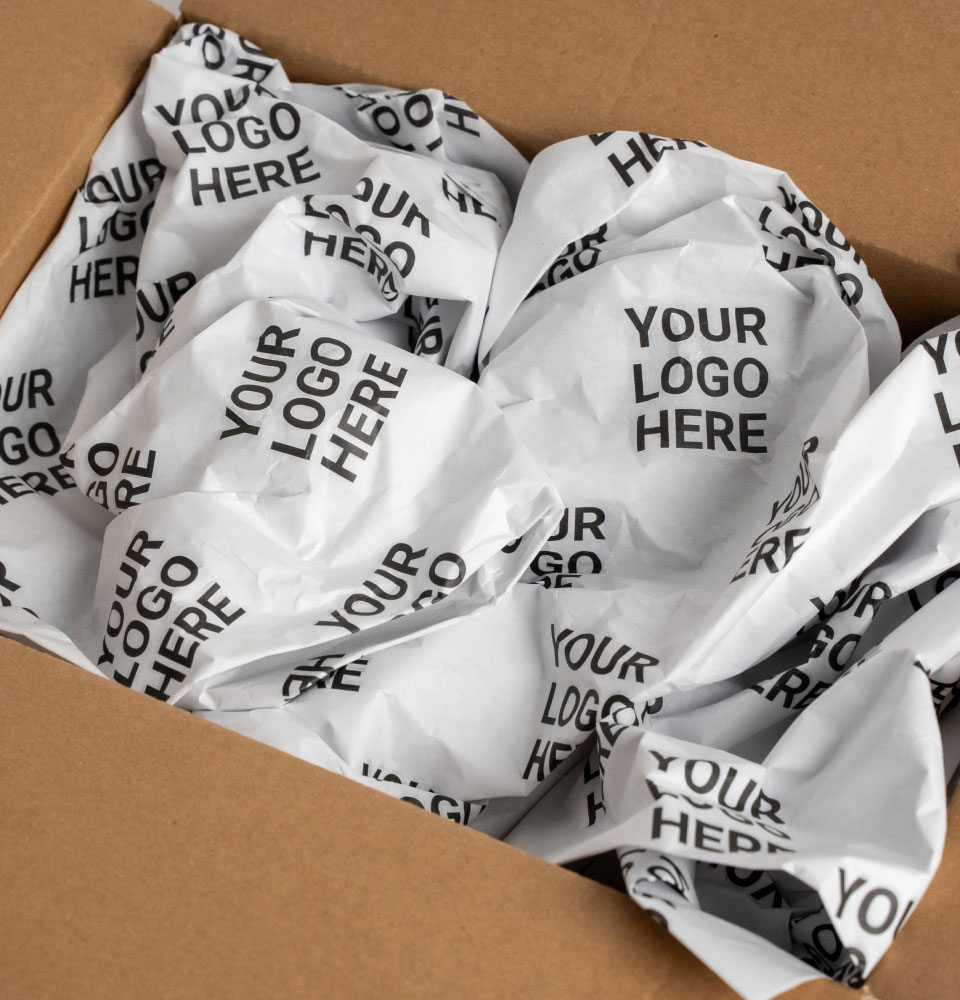 Crumpled white packing paper printed repeatedly with the text 'YOUR LOGO HERE' inside a cardboard box.