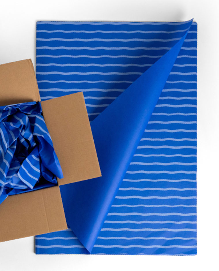 Blue sheets with light blue wavy stripes, one folded and another crumpled in a cardboard box.