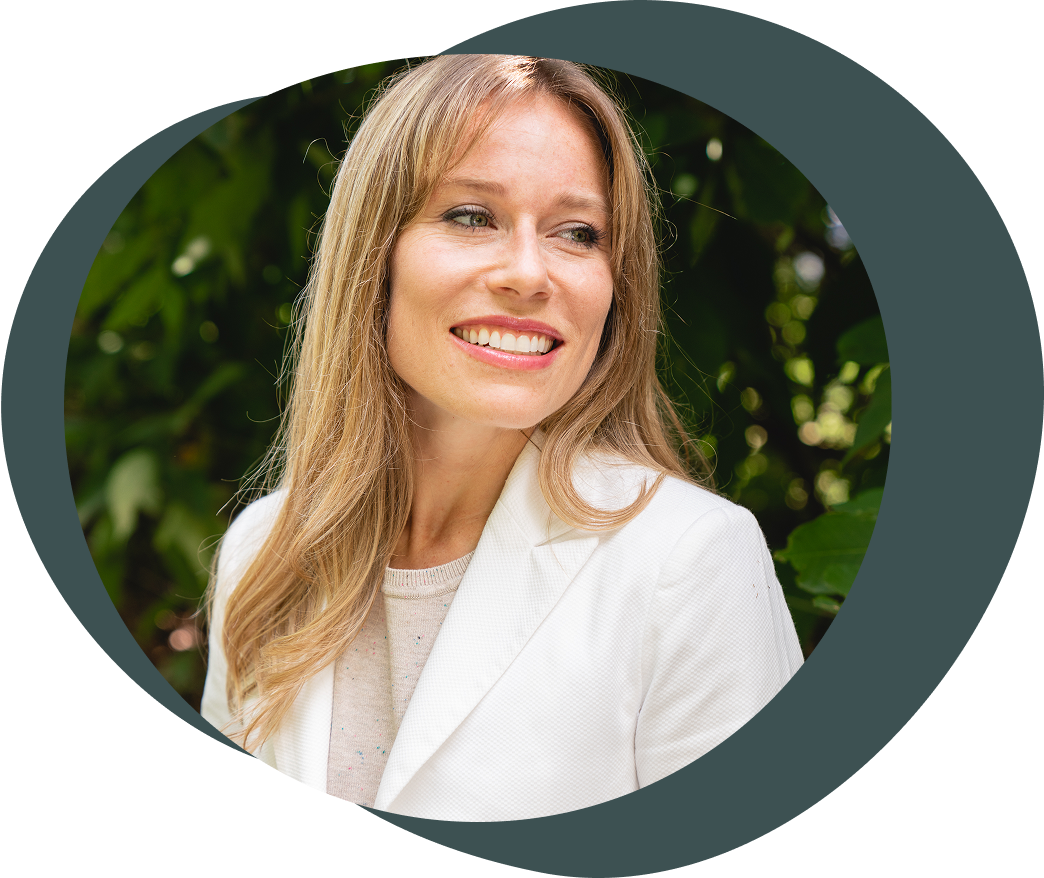 Photo of a blonde woman, sitting at a modern desk with her hands folded in front of her Macbook