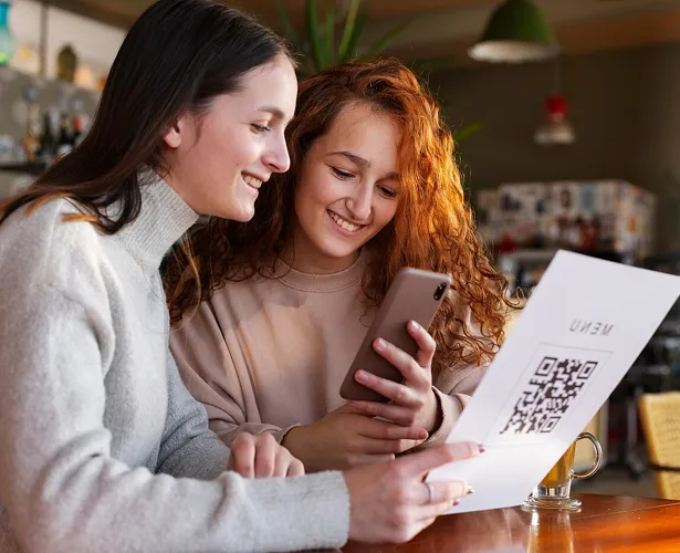 Clientas en mesa usando código QR para ver el menú