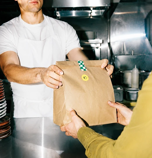 Personal de restaurante entrega un pedido para llevar a un cliente