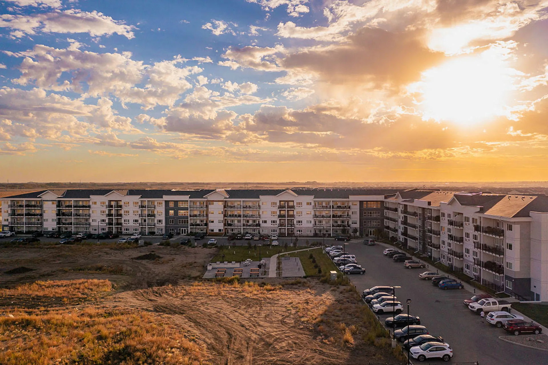 An updated apartment building complex with a beautiful sunset in the background.