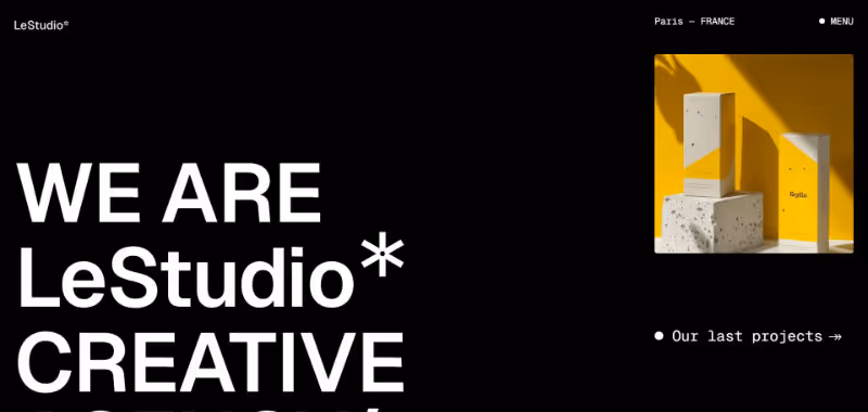 Black webpage with bold white text reading 'WE ARE LeStudio CREATIVE' and a photo of two yellow and white minimalist product boxes casting shadows on a vibrant yellow background.