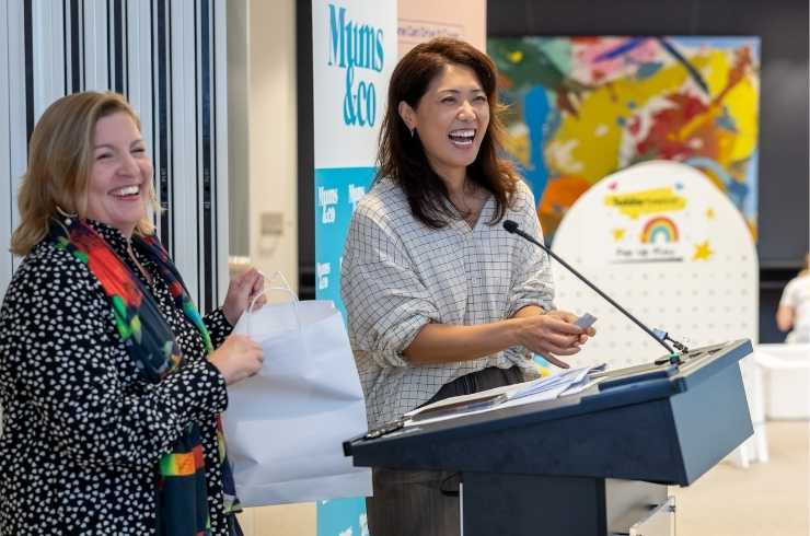 Close-up of a woman with long brown hair looking thoughtfully to the right against a blurred neutral background.