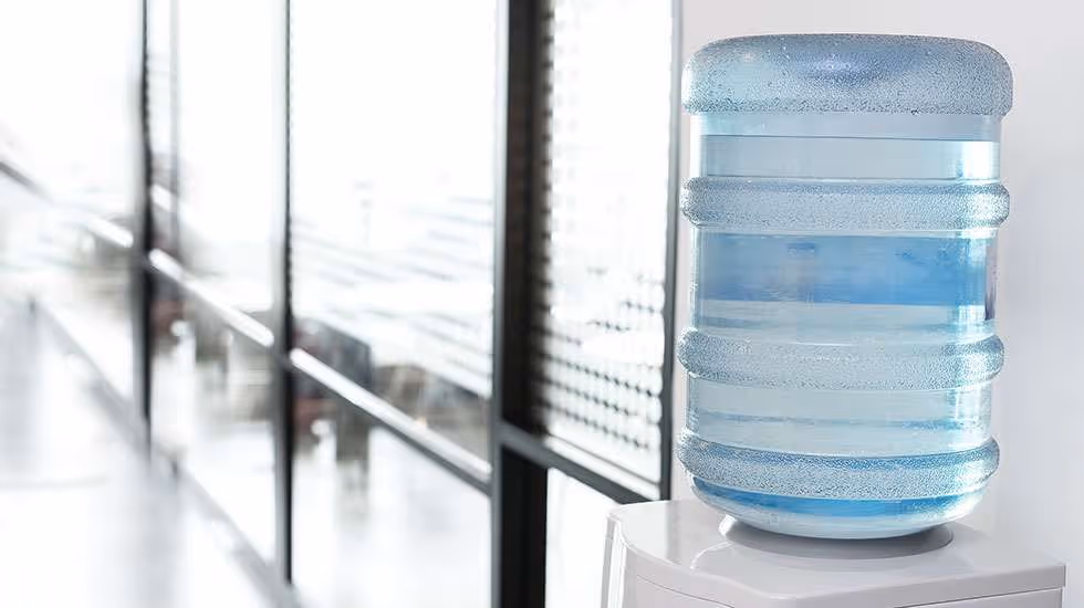 Office bottled water cooler with large refillable water container.