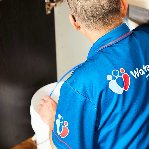 Technician installing a filtered water tap system under kitchen sink.