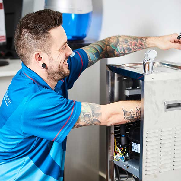Technician installing a filtered water tap system under kitchen sink.