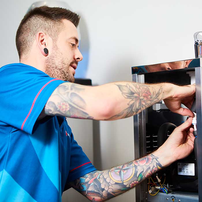Technician installing a filtered water tap system under kitchen sink.