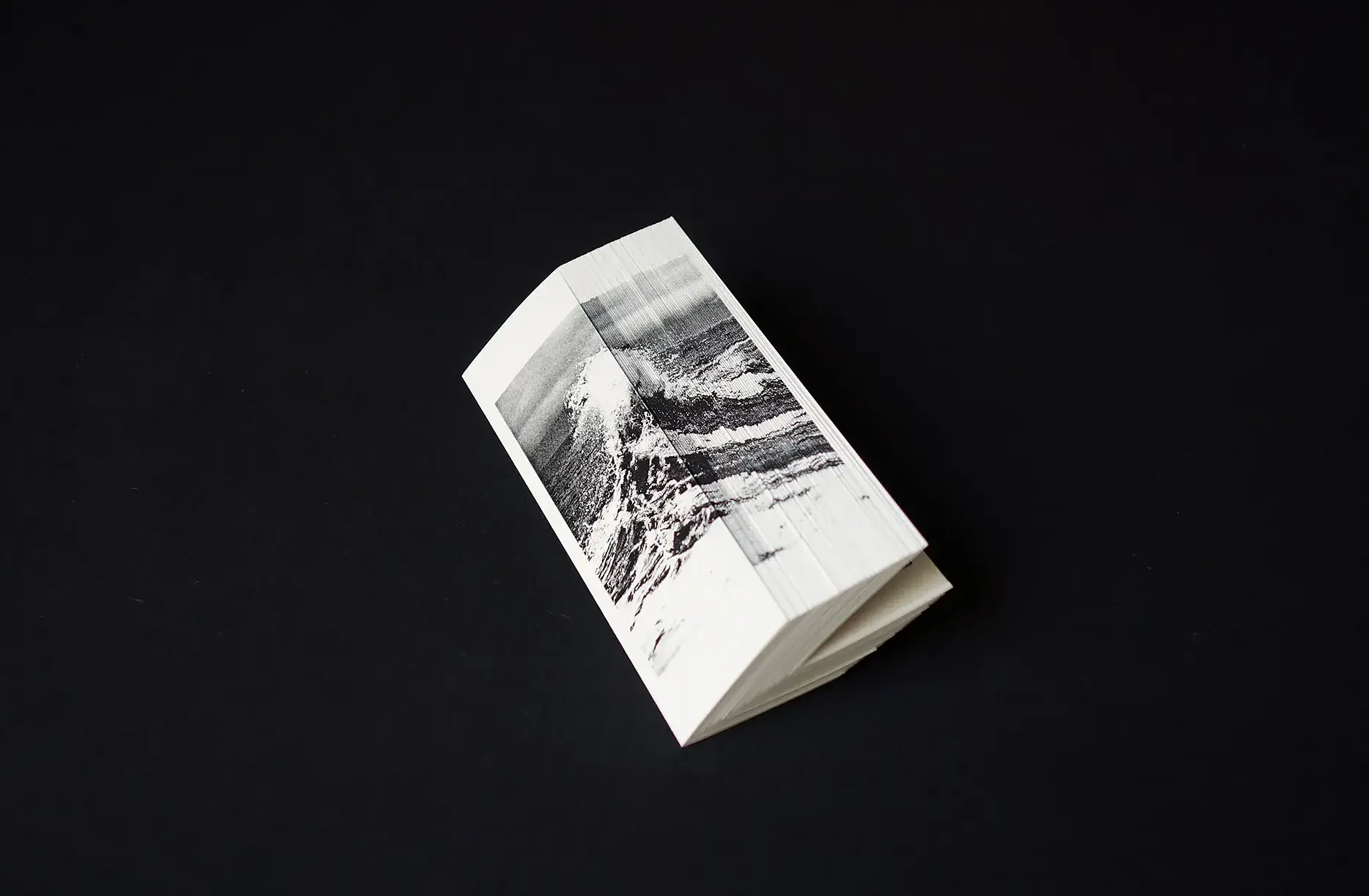 Portfolio Archive from graphic designer Laura Jouan, 2015-present. "Thick folded book with a black-and-white photo of ocean waves printed across its pages on a black background."
