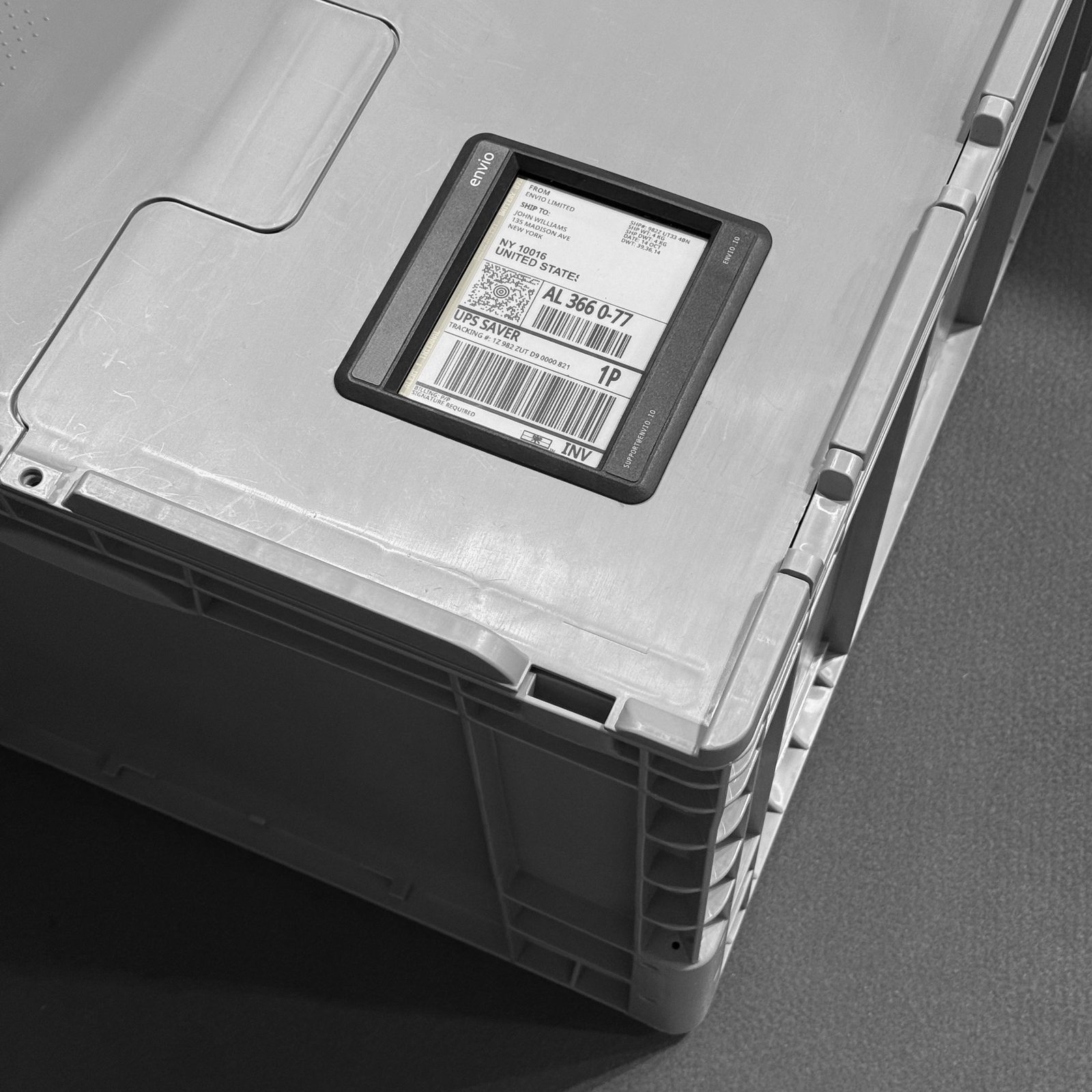 A plastic shipping crate with a digital shipping label displaying barcodes and address information.