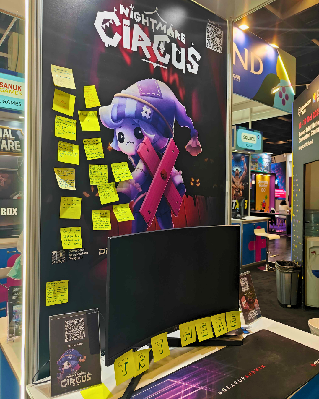 Photograph of FairPlay Studios' Nightmare Circus booth at Gamescom. The key art featuring a concerned cartoon character wearing a sleep hat os on the backdrop, which is also covered in sticky notes from players who have played the game.