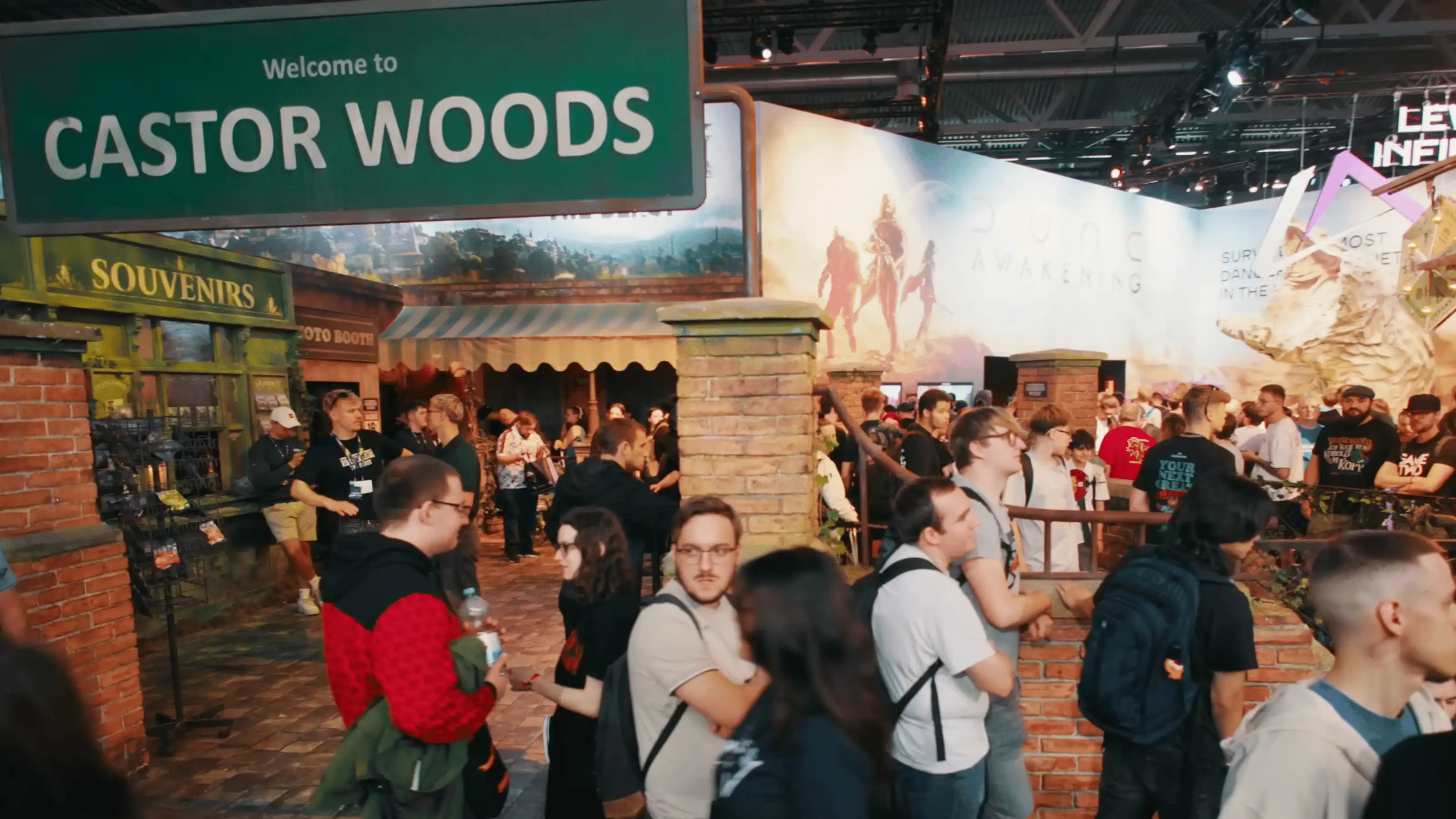 Photograph of Dying Light's booth at Gamescom, featuring a large immersive set from Castor Woods, with a giant welcome sign, & store-fronts to mimic a small village.