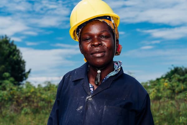 A worker wearing a yellow hard hat in a field filled with crops.
