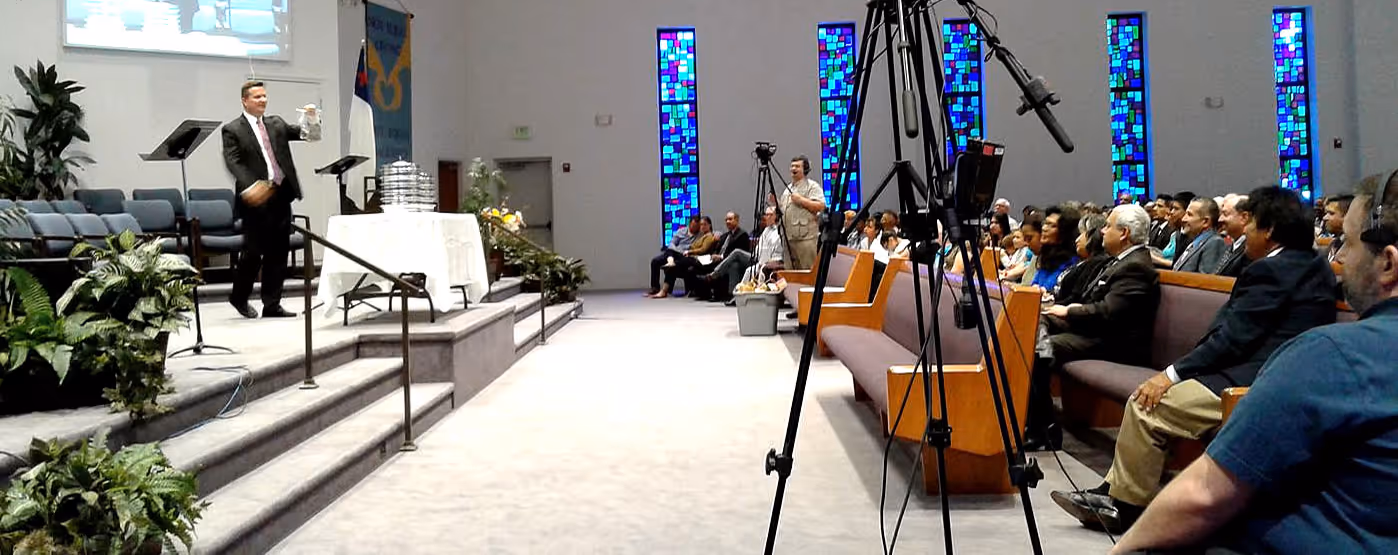 Congregation gathered for a Sunday service in a bright sanctuary with stained glass windows