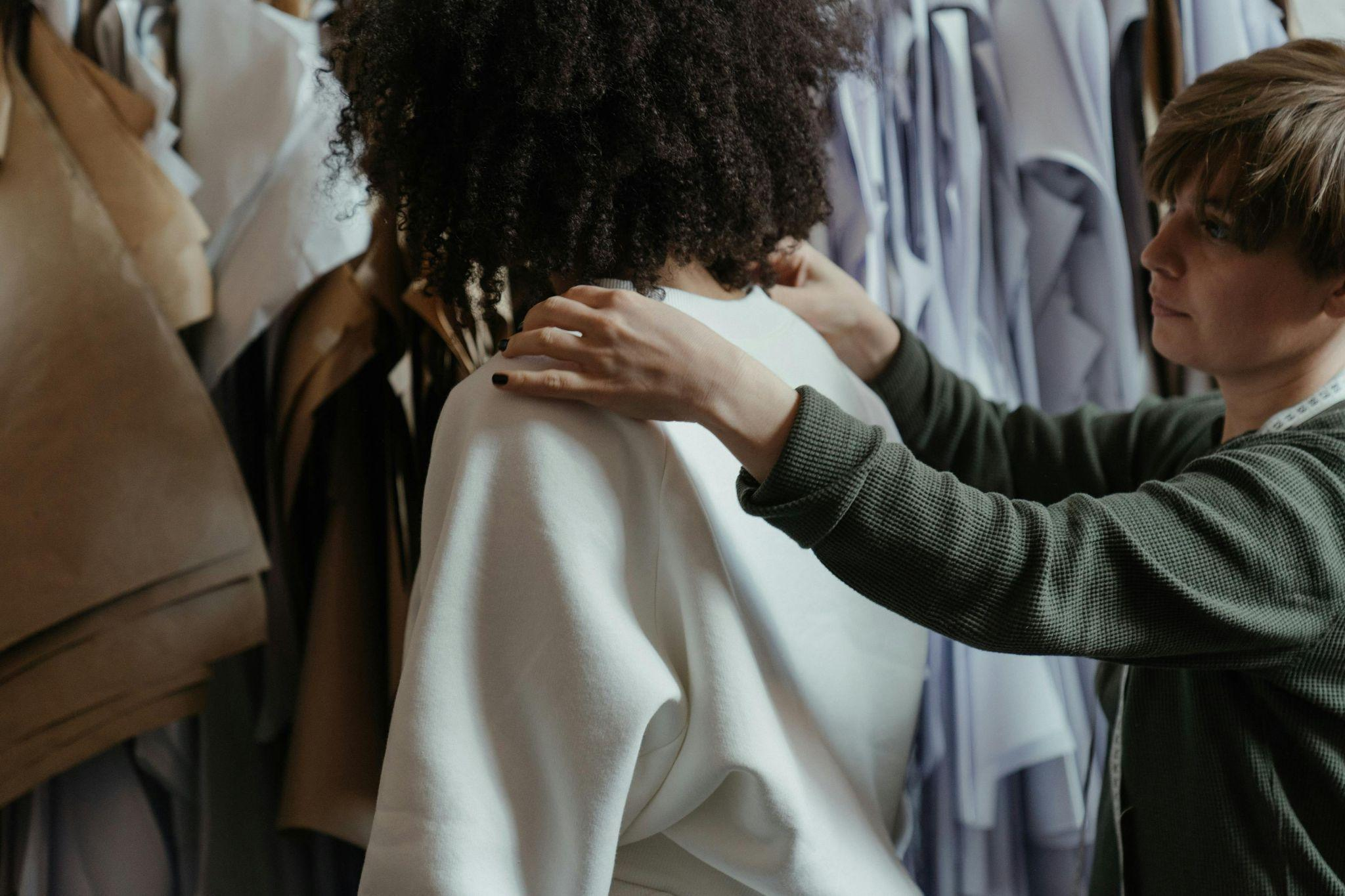 A designer measuring a garment fit on a model in a studio.