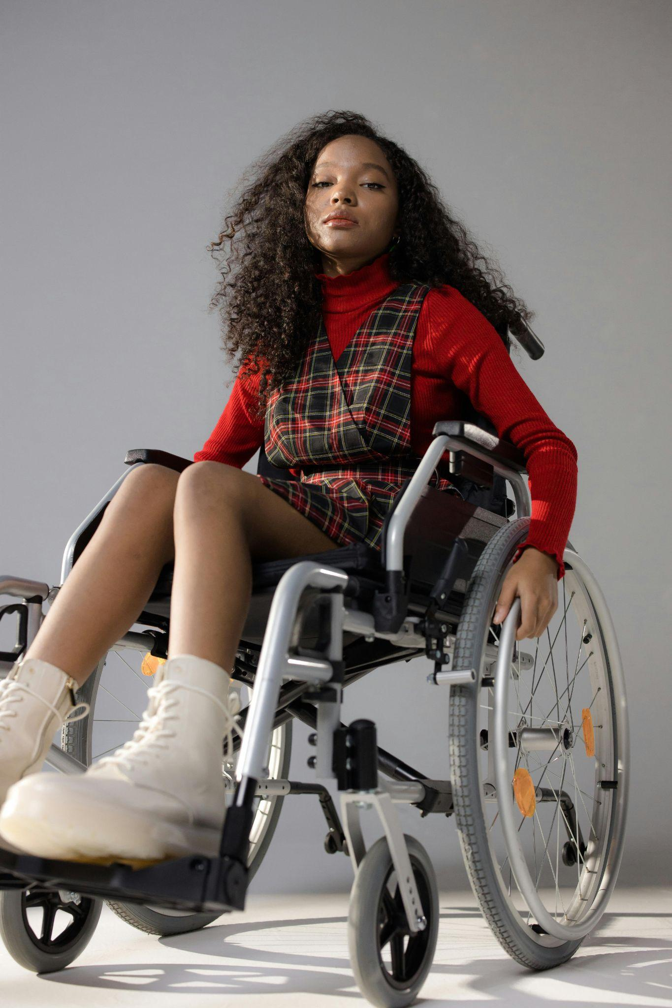 Woman in a wheelchair wearing a red turtleneck and a plaid dress