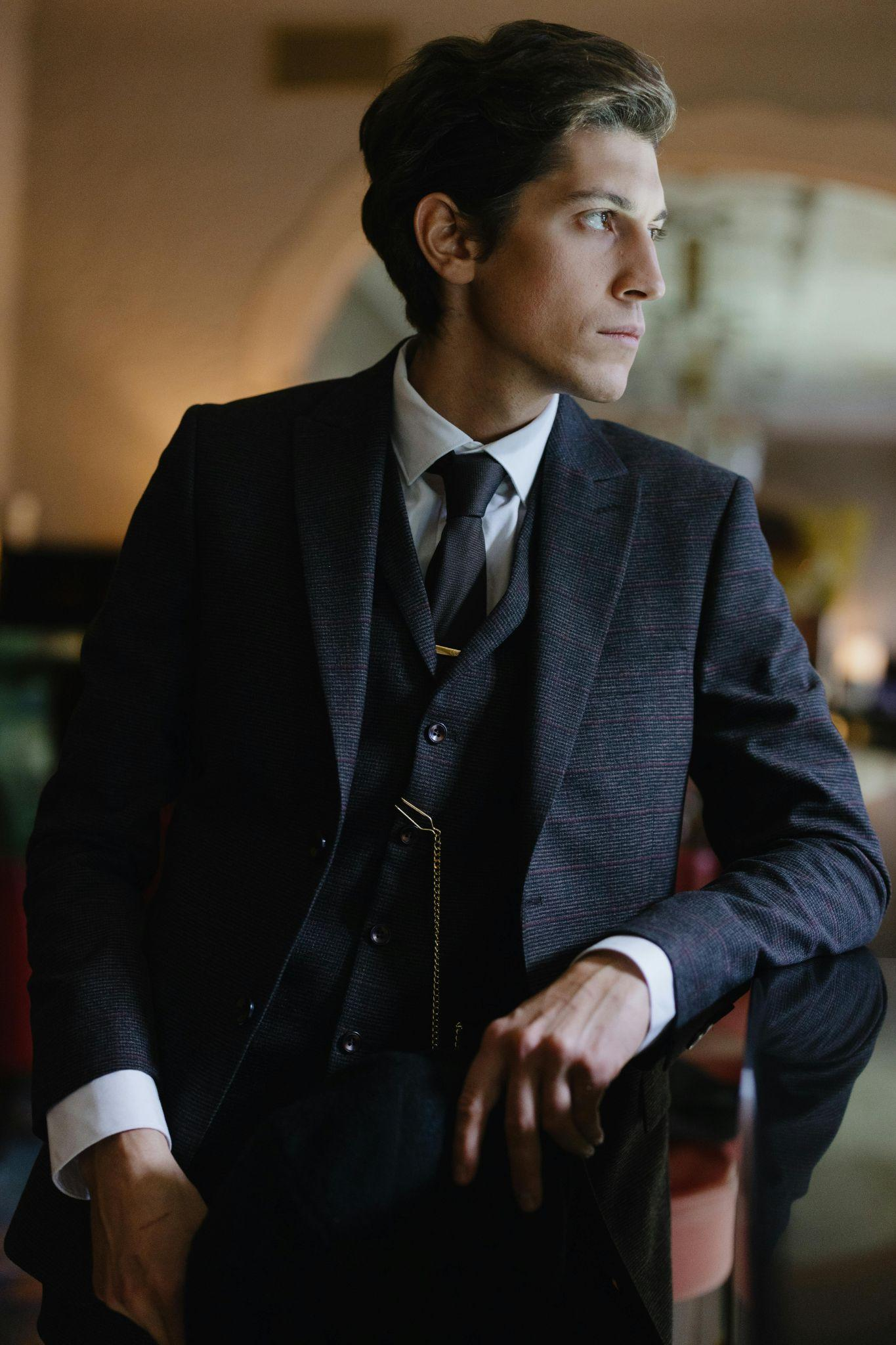 A man in a suit, standing and posing.