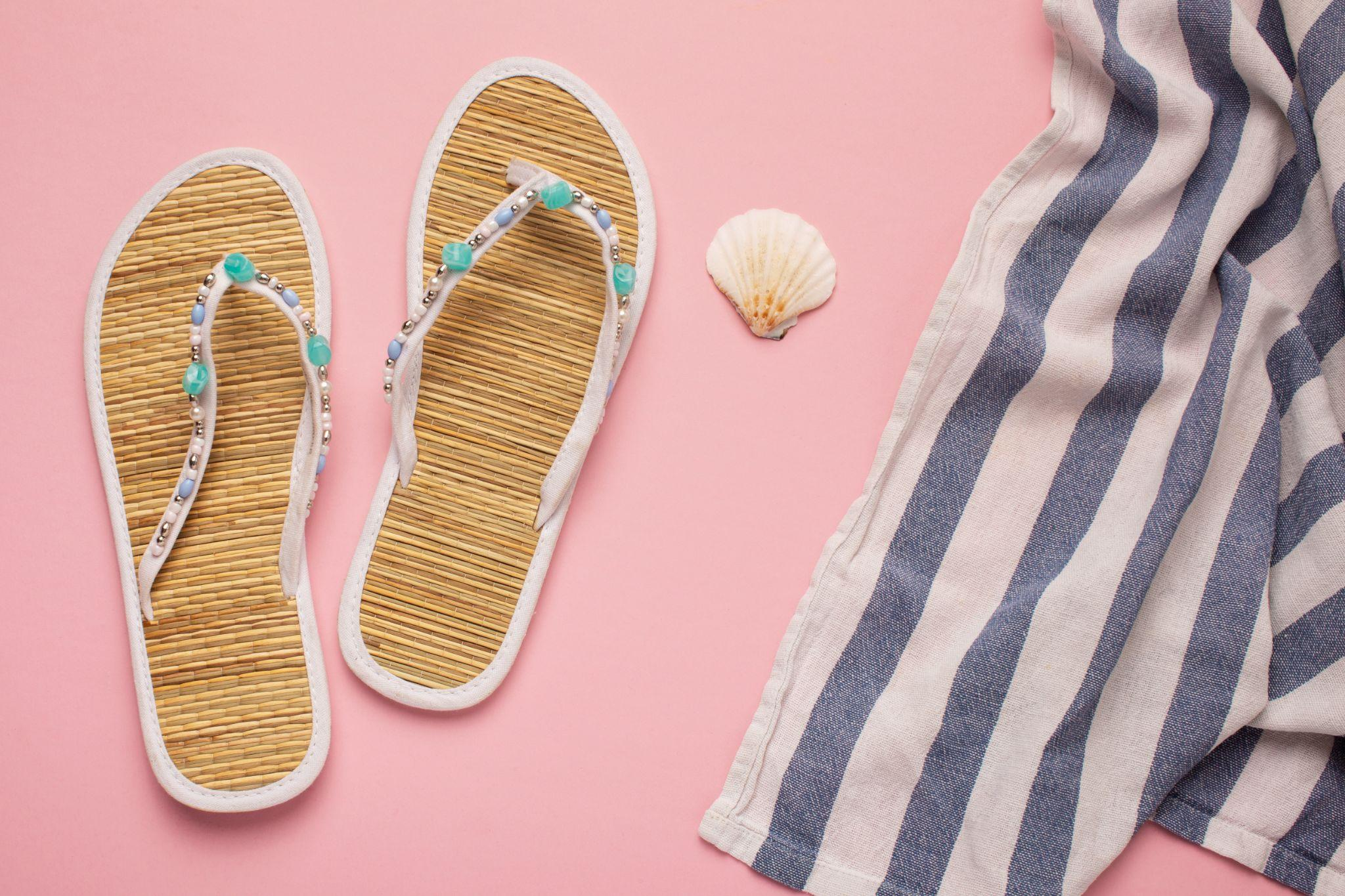 Flip-flops and swimwear on a pink background with a seashell