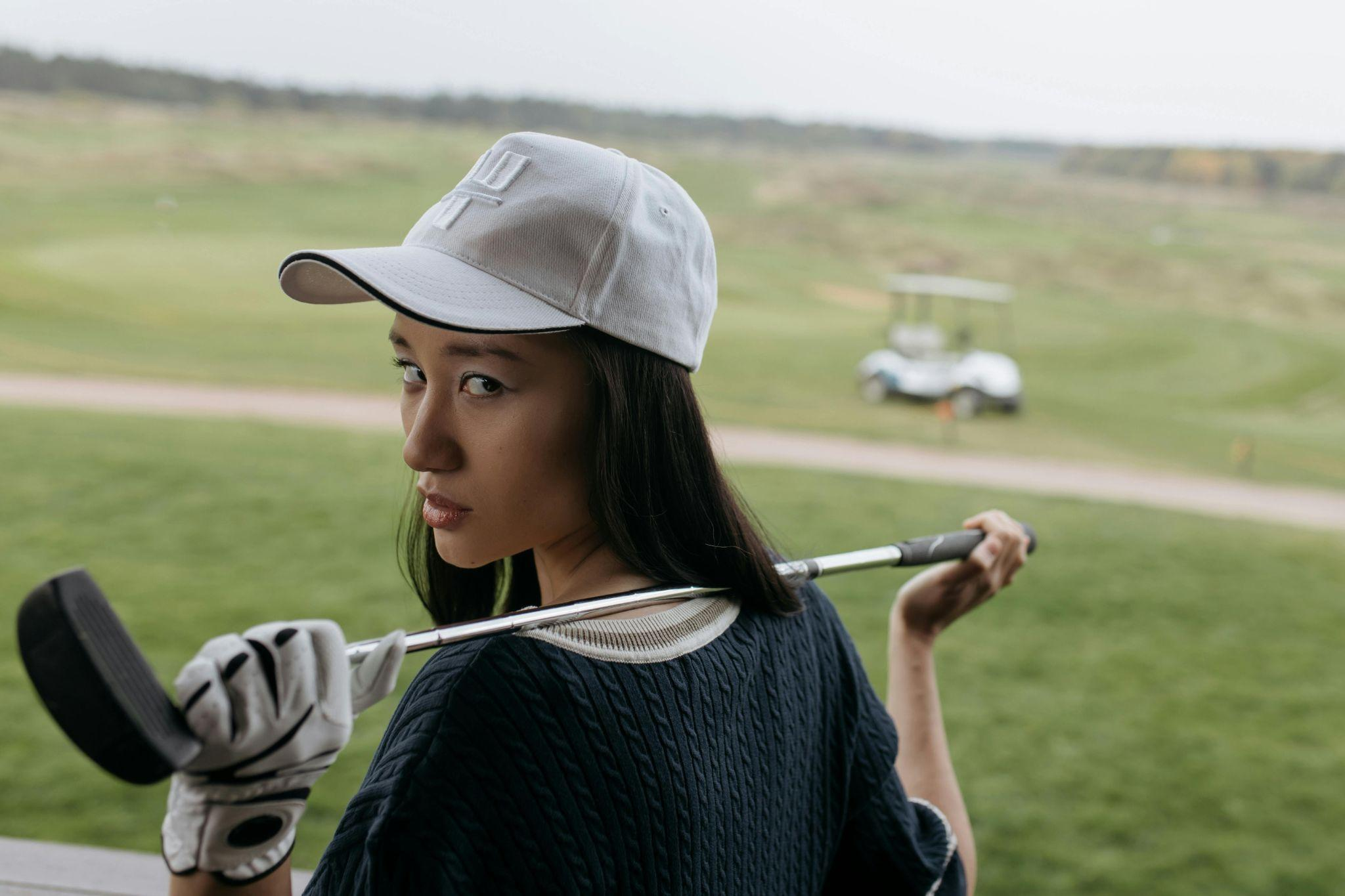 Woman holding a golf club over her shoulder while standing on a golf course.