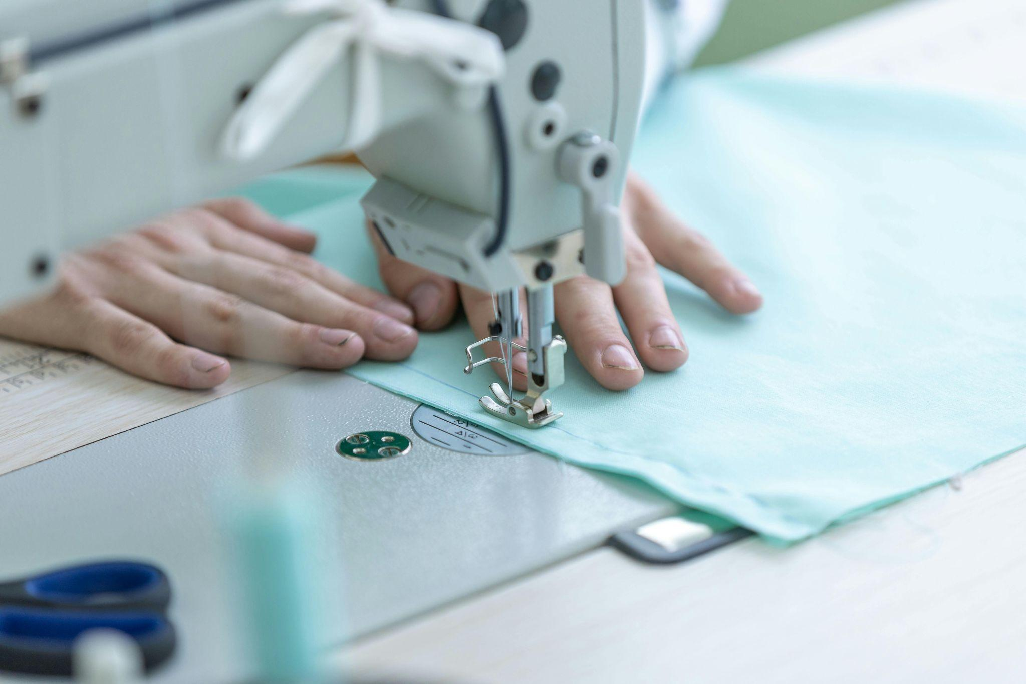 Hands guiding fabric through a sewing machine