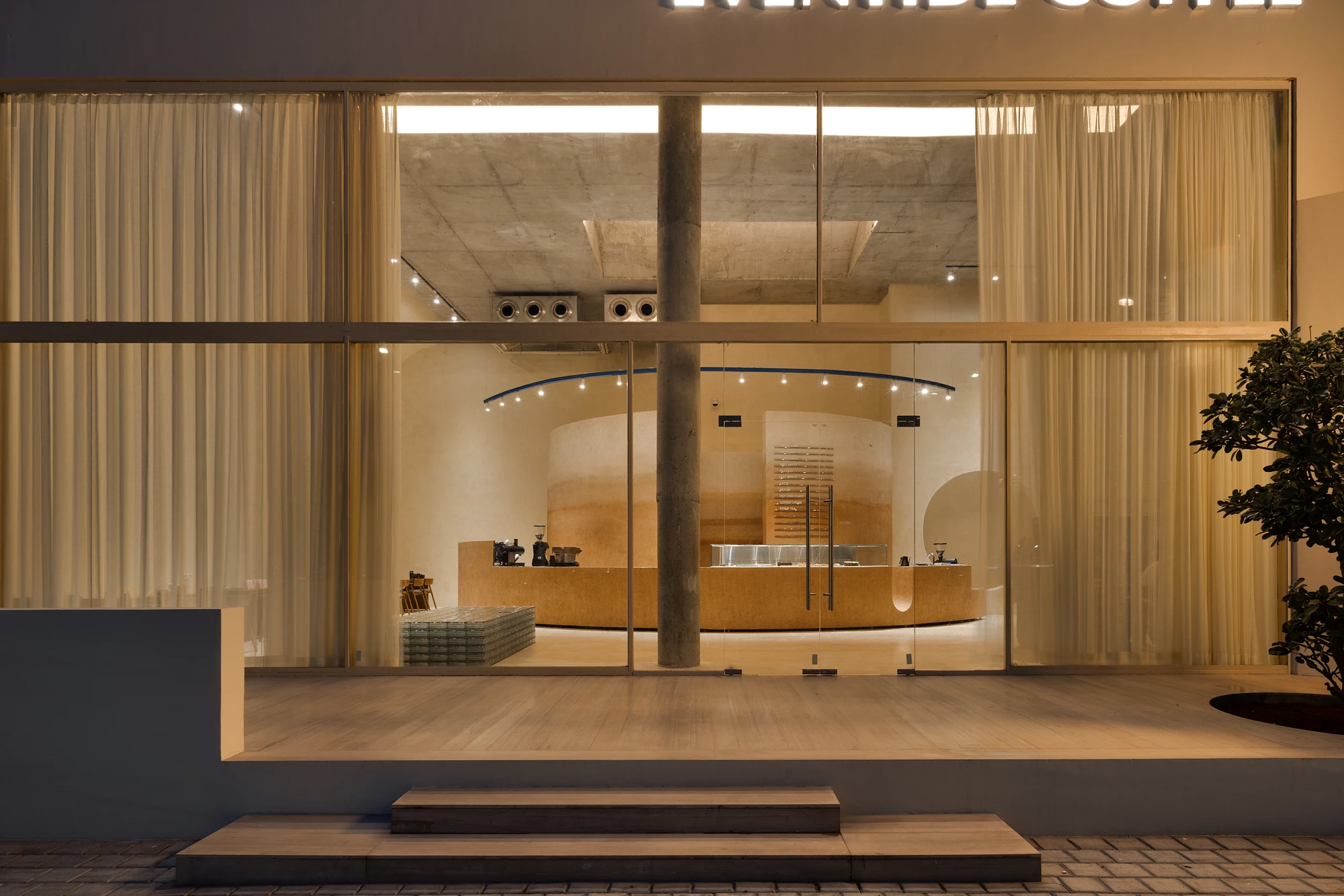 Eventide Coffee by BILLBOARDS in Chennai India, coastal cafe interior with elliptical counter and skylight, earthy tones and curved architectural elements inspired by the Madras beach