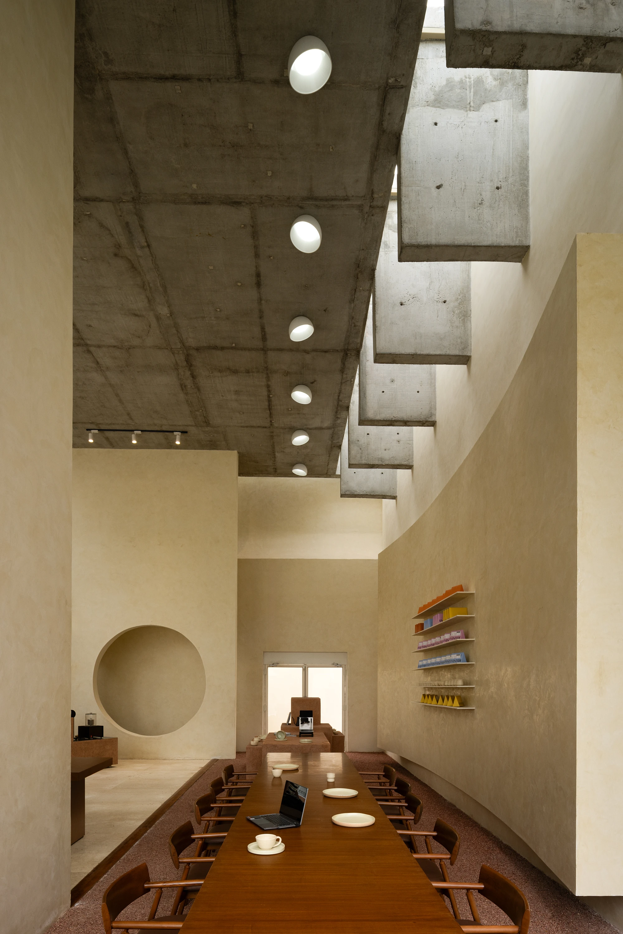 Eventide Coffee by BILLBOARDS in Chennai India, coastal cafe interior with elliptical counter and skylight, earthy tones and curved architectural elements inspired by the Madras beach