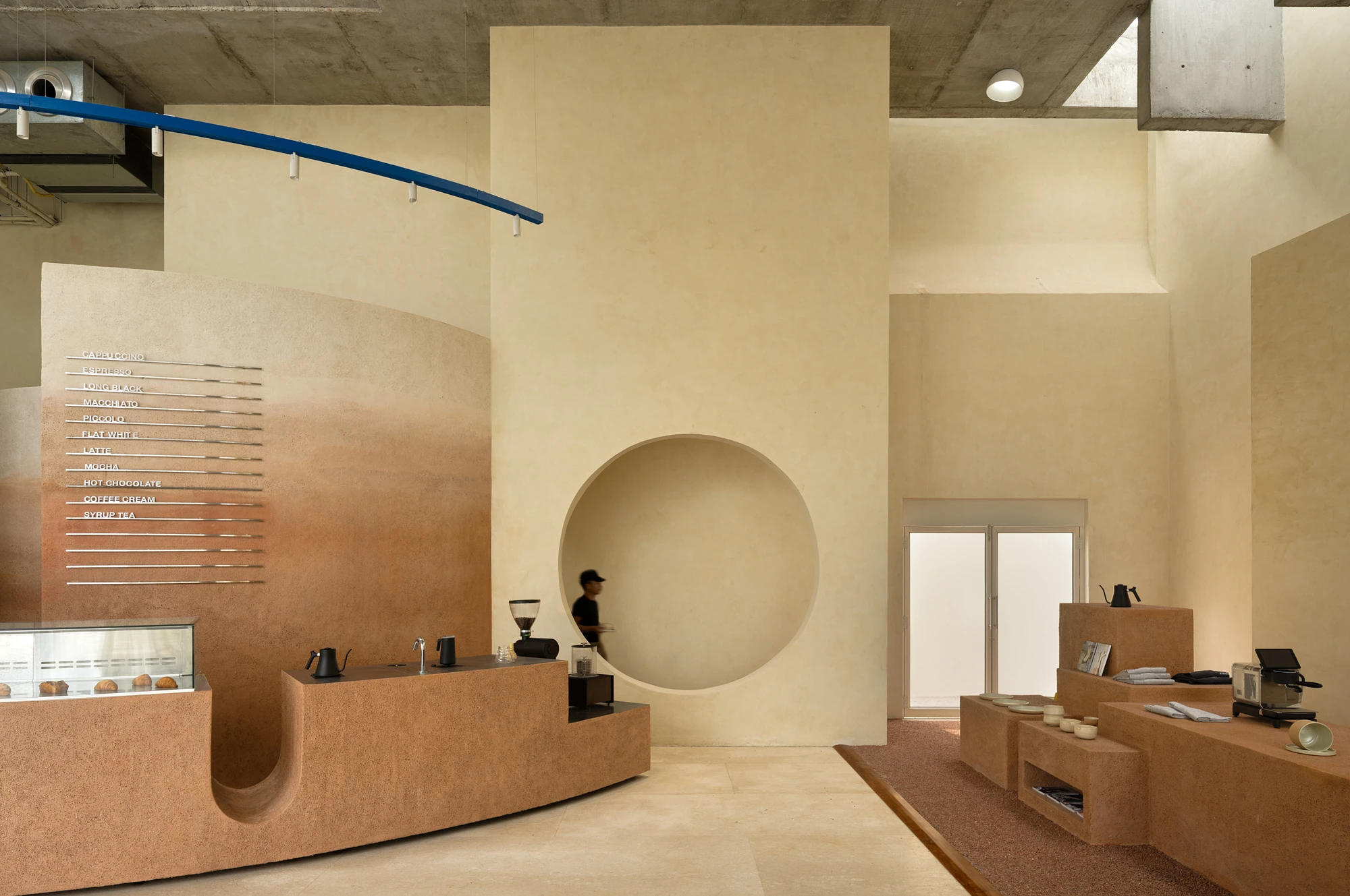 Eventide Coffee by BILLBOARDS in Chennai India, coastal cafe interior with elliptical counter and skylight, earthy tones and curved architectural elements inspired by the Madras beach