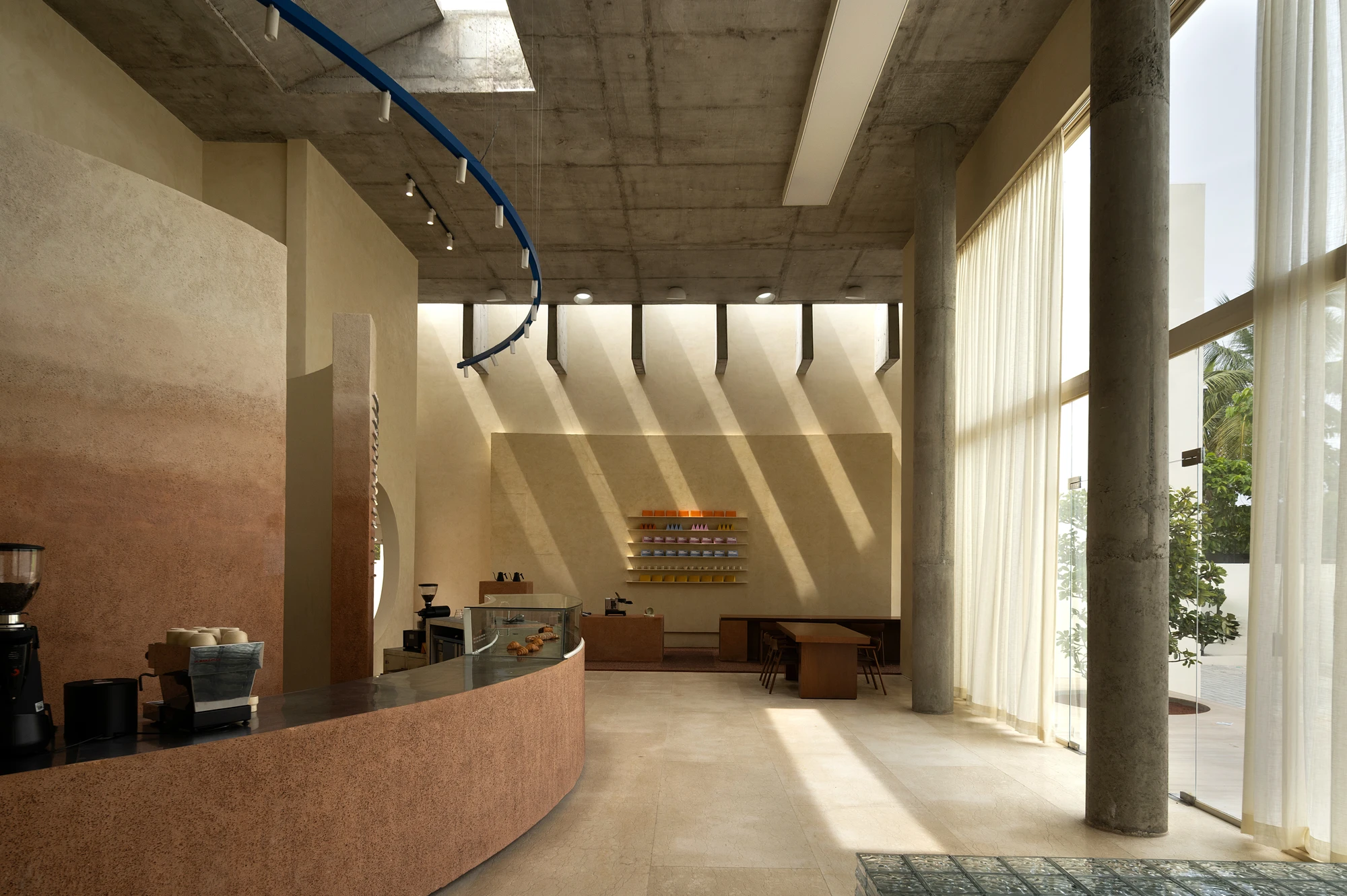 Eventide Coffee by BILLBOARDS in Chennai India, coastal cafe interior with elliptical counter and skylight, earthy tones and curved architectural elements inspired by the Madras beach