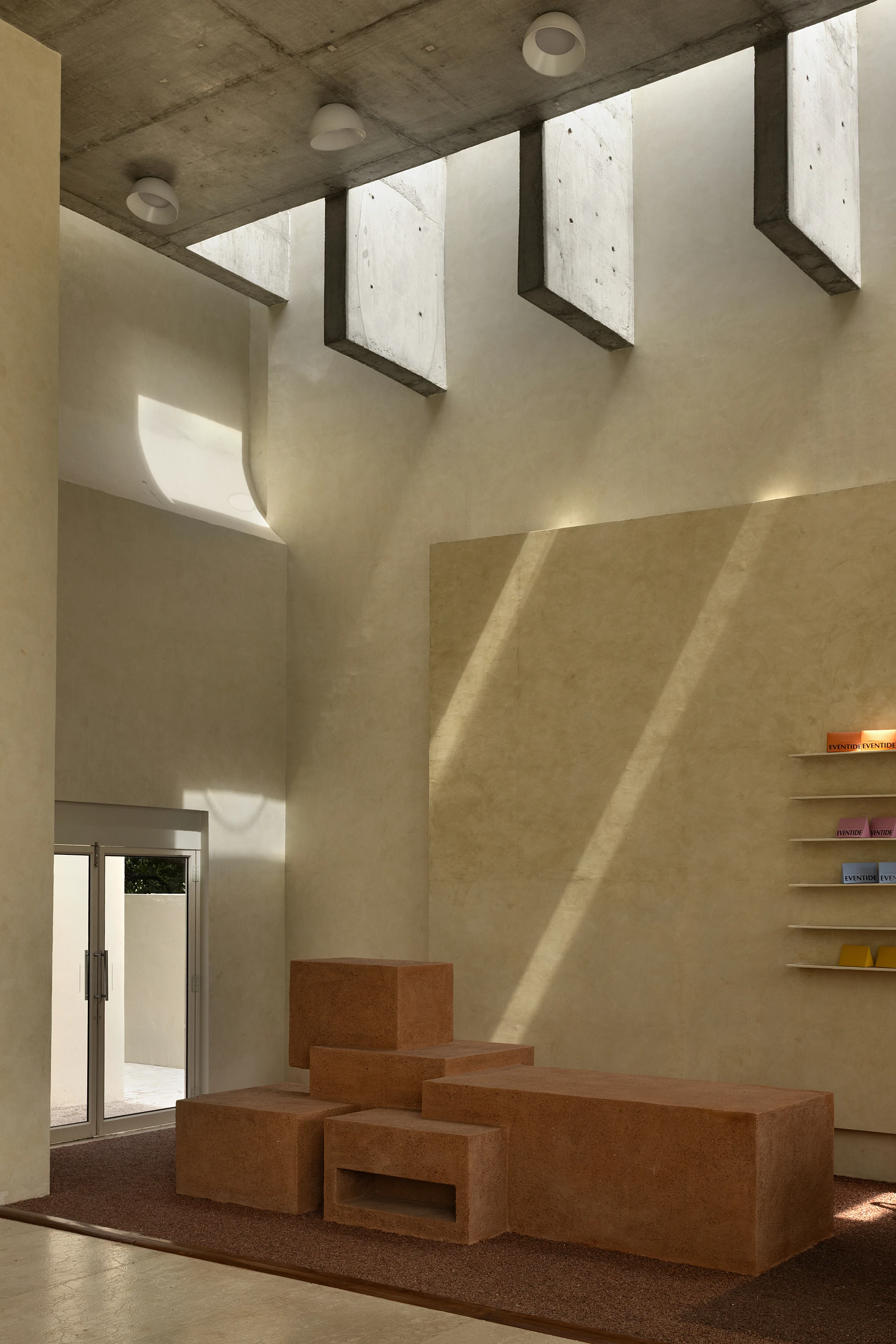 Eventide Coffee by BILLBOARDS in Chennai India, coastal cafe interior with elliptical counter and skylight, earthy tones and curved architectural elements inspired by the Madras beach