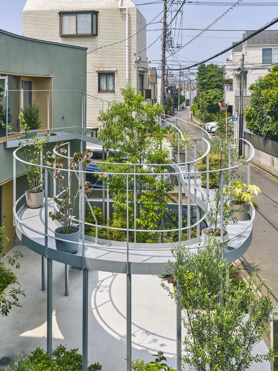 House in Nakano by HOAA — A circular elevated terrace cantilevers above street level, its white floor and continuous metal railing creating a geometric counterpoint to the dense...