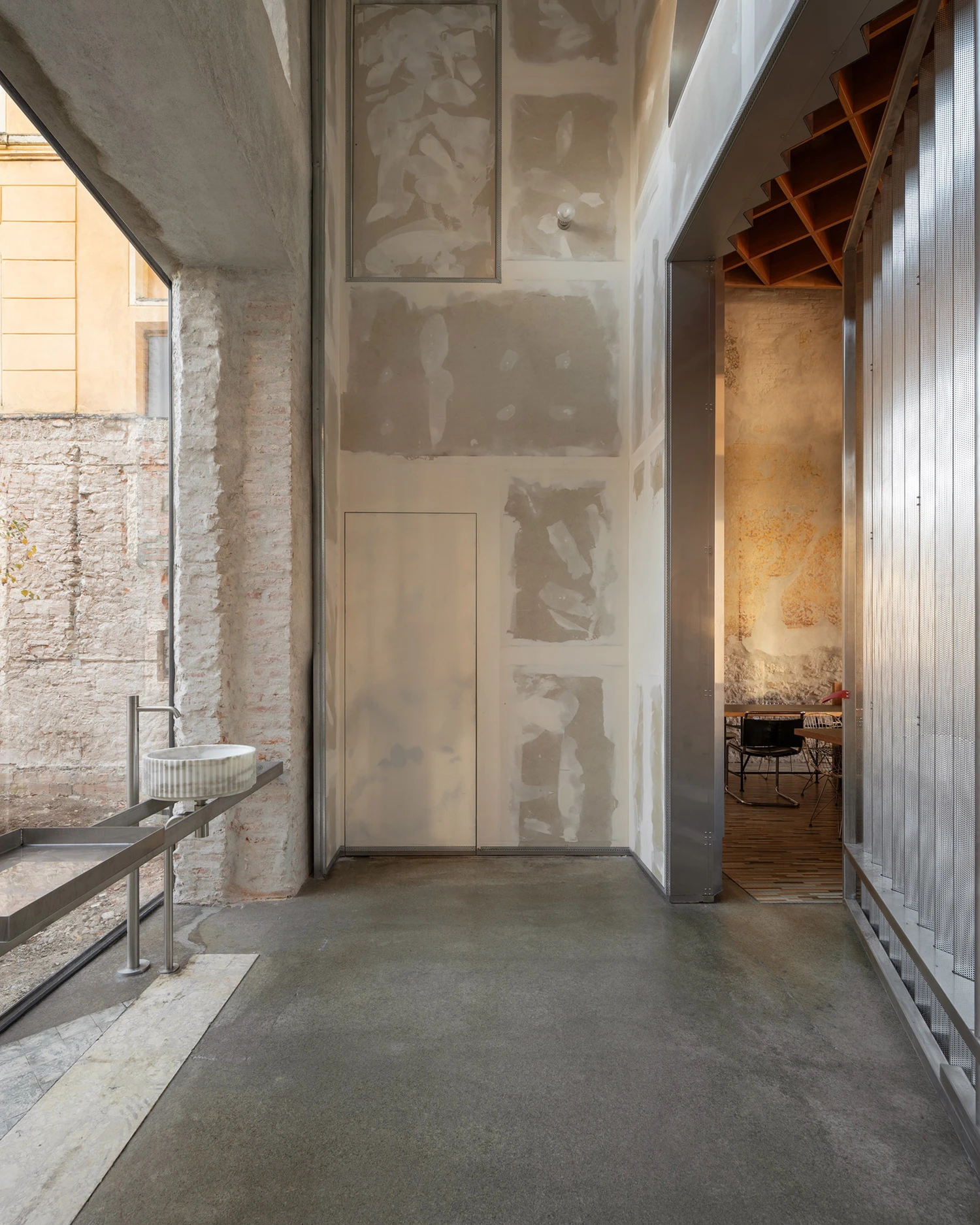Caffè Nazionale by AMAA in Arzignano Italy, adaptive reuse of 19th-century palazzo with pleated stainless steel walls, okumè plywood ceiling and preserved historical patinas
