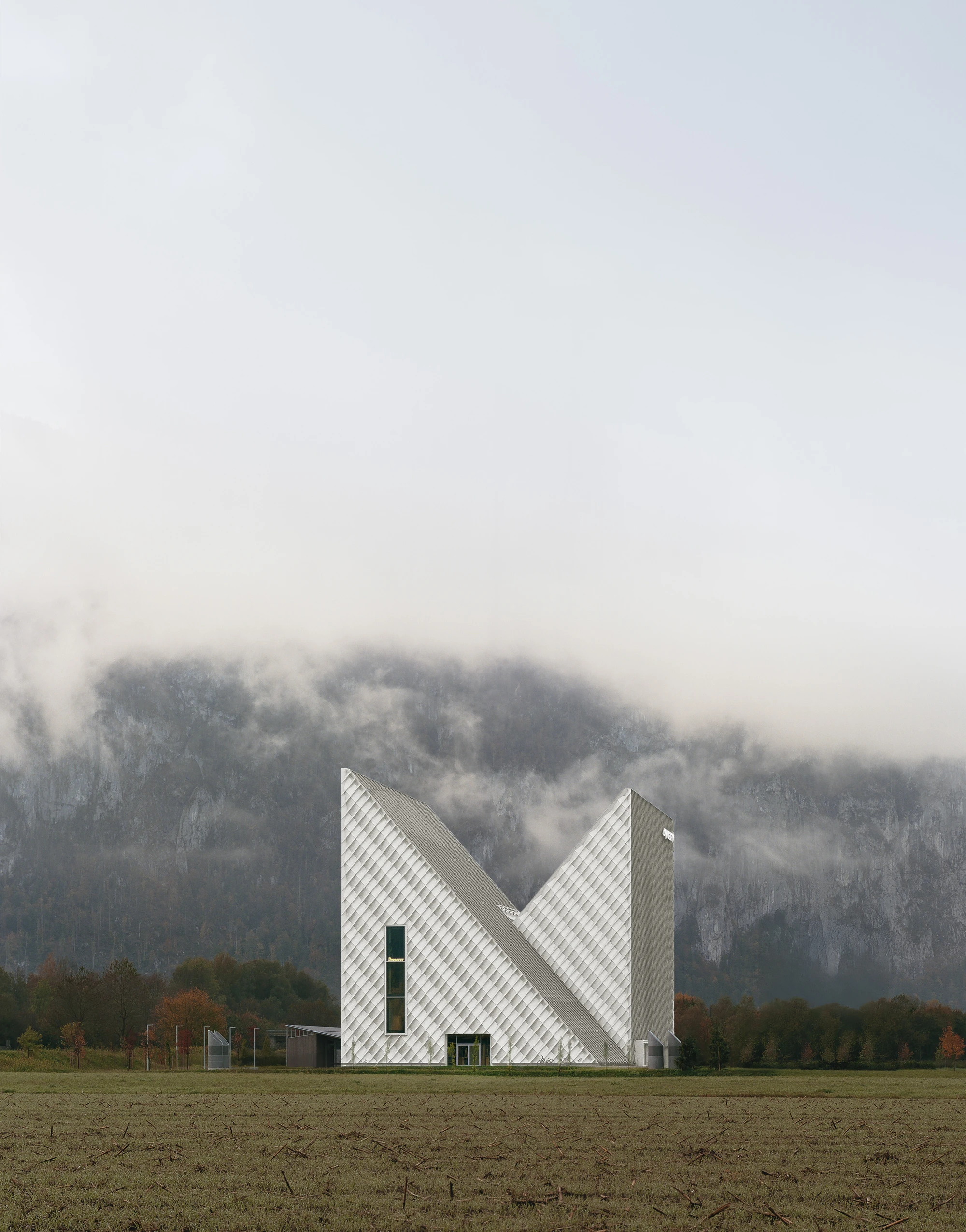 Dynafit Headquarters Speedfactory by Barozzi Veiga in Kiefersfelden Germany, twin pyramidal corporate building with diagonal metal lattice facade set against alpine landscape
