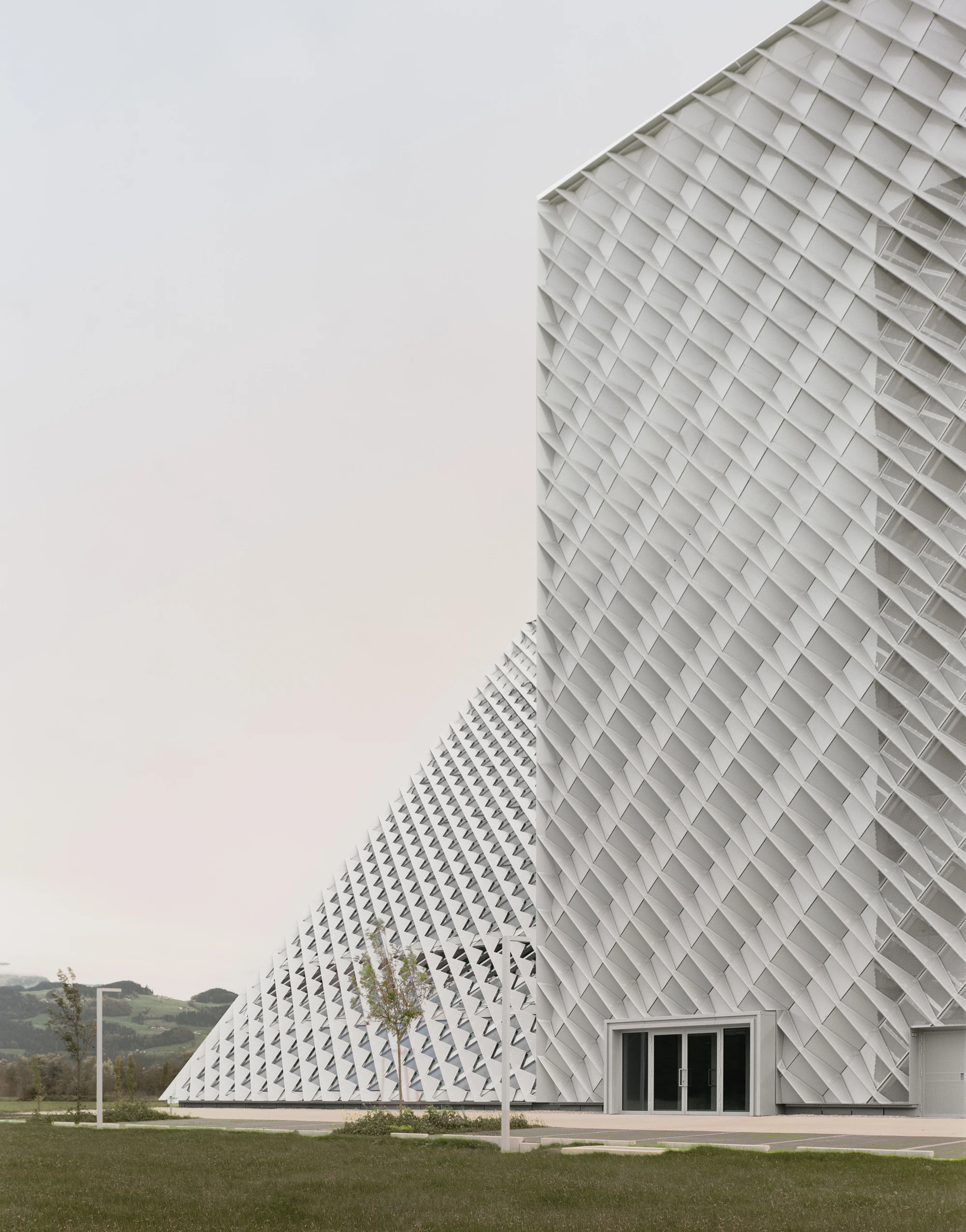 Dynafit Headquarters Speedfactory by Barozzi Veiga in Kiefersfelden Germany, twin pyramidal corporate building with diagonal metal lattice facade set against alpine landscape