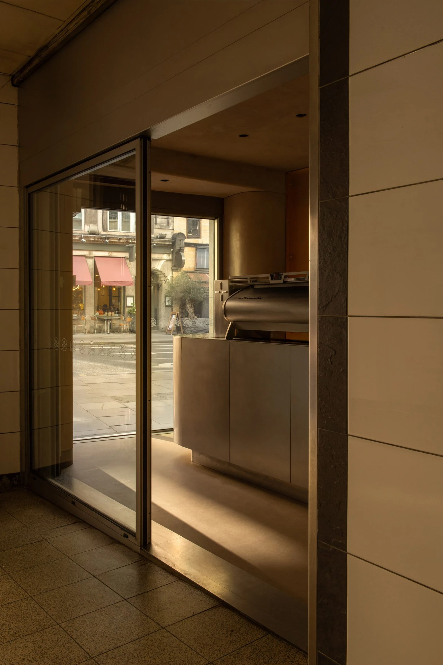 Joe Blake's Holborn coffee shop by EBBA in London tube station, minimalist interior with rounded stainless steel counter and milky translucent storage wall, sand-coloured plaster ceiling
