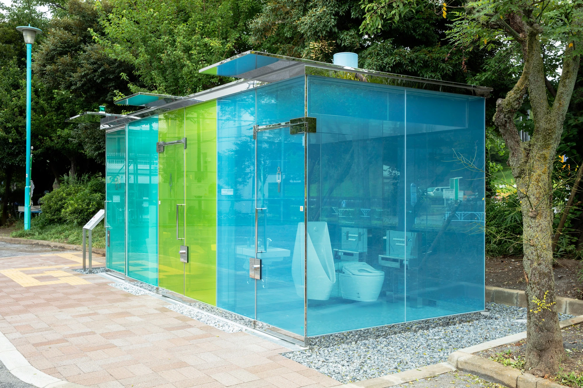 Transparent public toilet by Shigeru Ban in Shibuya Tokyo, coloured glass walls that turn opaque when locked at night glowing like a lantern, Tokyo Toilet project by Nippon Foundation