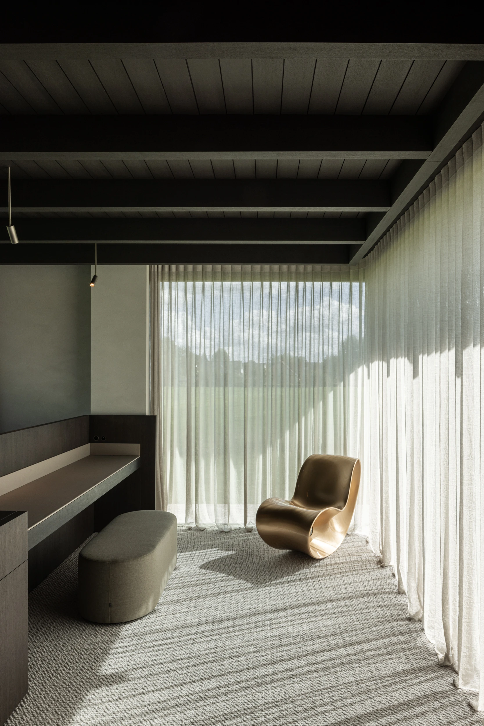 Villa WIGO by CAS Architecten — A ground-floor interior flooded with diffuse daylight through full-height vertical blinds, creating linear shadow patterns across a textured wool carpet.