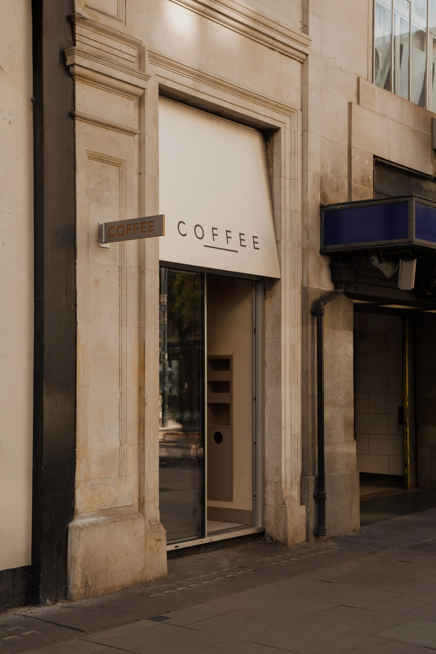 Joe Blake's Holborn coffee shop by EBBA in London tube station, minimalist interior with rounded stainless steel counter and milky translucent storage wall, sand-coloured plaster ceiling