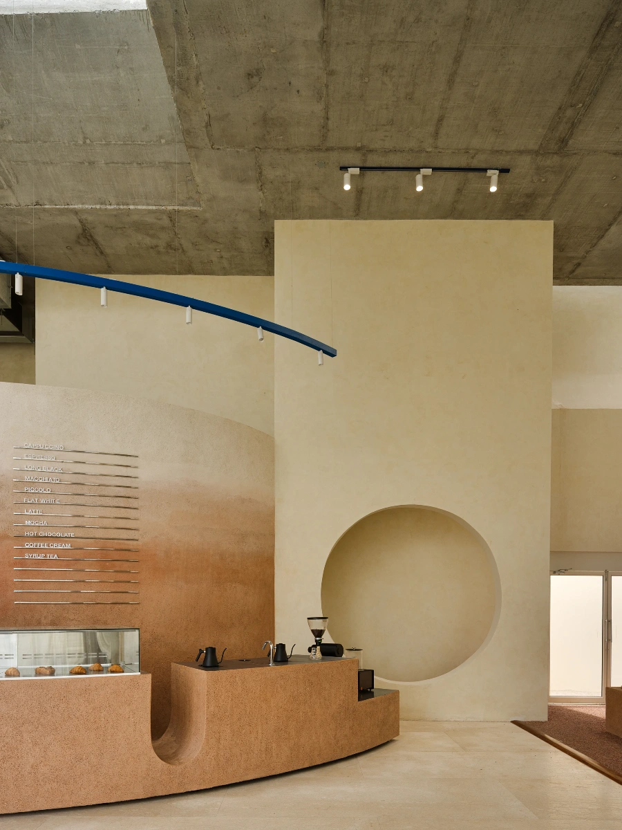 Eventide Coffee by BILLBOARDS in Chennai India, coastal cafe interior with elliptical counter and skylight, earthy tones and curved architectural elements inspired by the Madras beach