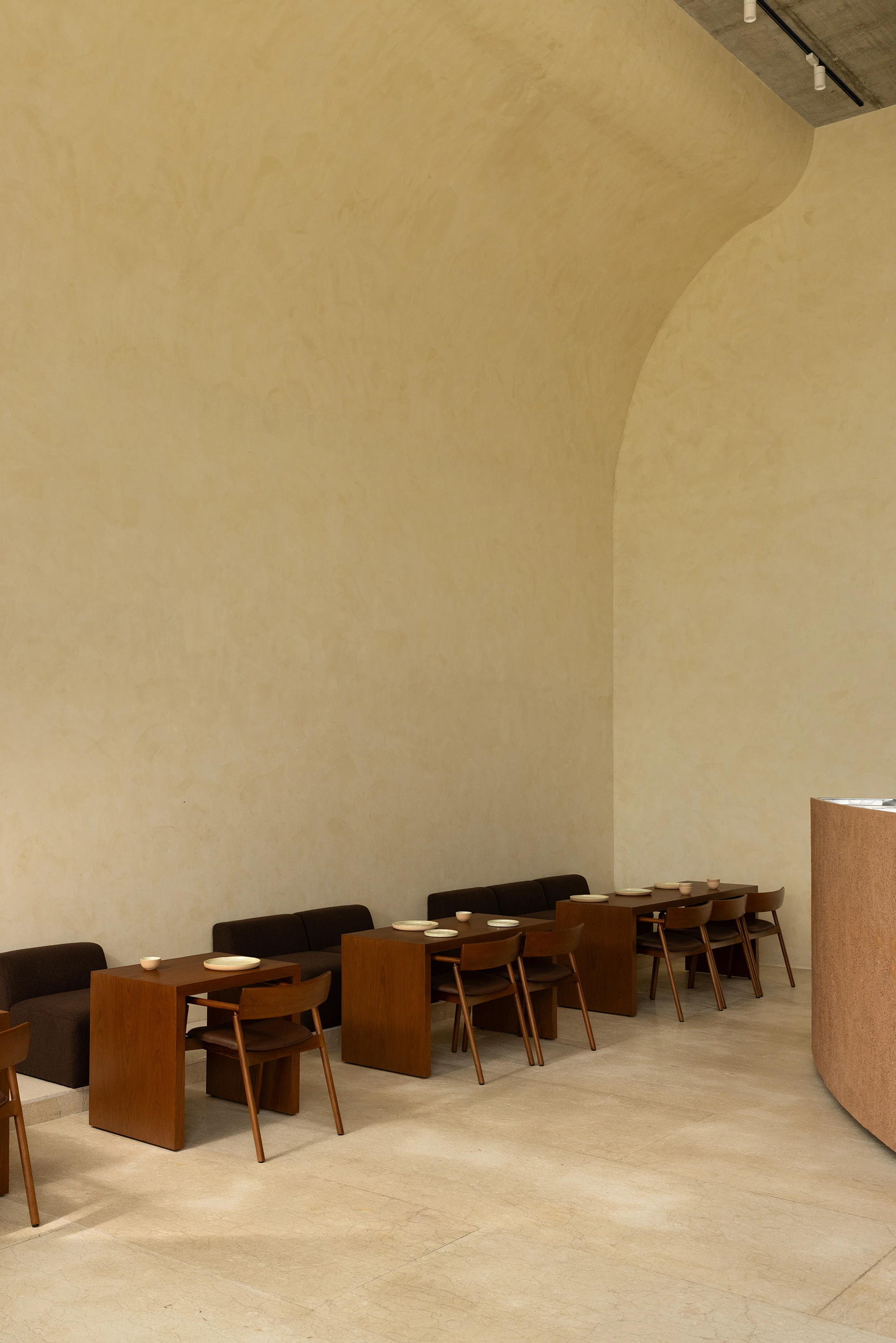 Eventide Coffee by BILLBOARDS in Chennai India, coastal cafe interior with elliptical counter and skylight, earthy tones and curved architectural elements inspired by the Madras beach