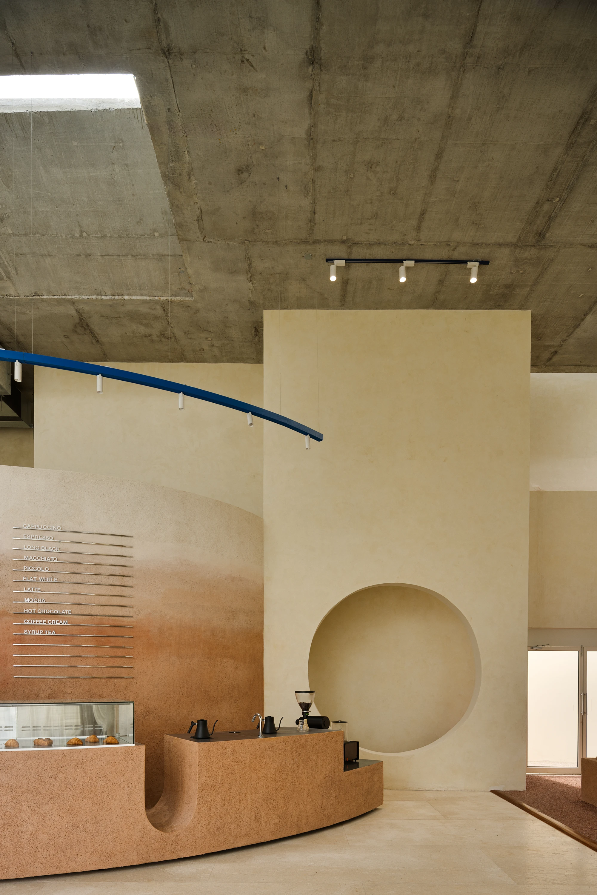 Eventide Coffee by BILLBOARDS in Chennai India, coastal cafe interior with elliptical counter and skylight, earthy tones and curved architectural elements inspired by the Madras beach