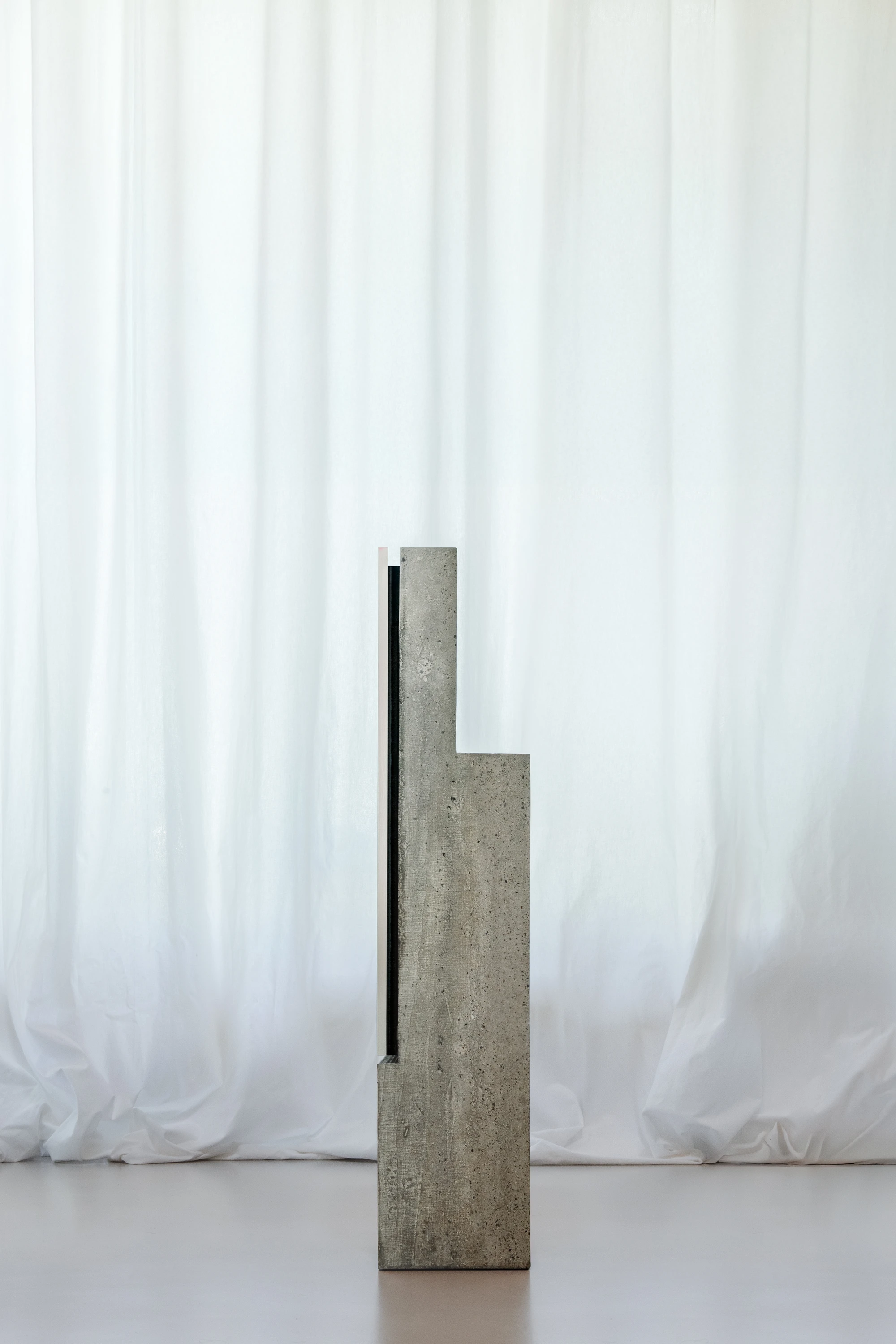 Concrete TV Stand by David Bard — David Bard's concrete television stand presents an L-shaped volumetric form in cast concrete, its surface revealing polished expanded clay aggregate...