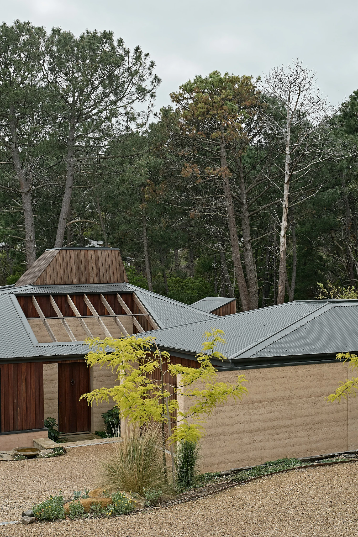 Homestead House by MRTN Architects — Homestead House presents a deliberate material honesty: rammed-earth walls display visible horizontal compaction striations beneath a corrugated metal roof...