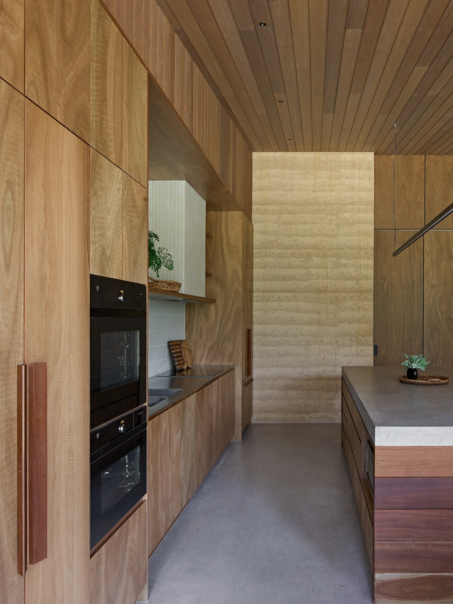 Homestead House by MRTN Architects — Interior kitchen gallery space lined in warm timber with vertical board cladding on walls and ceiling.