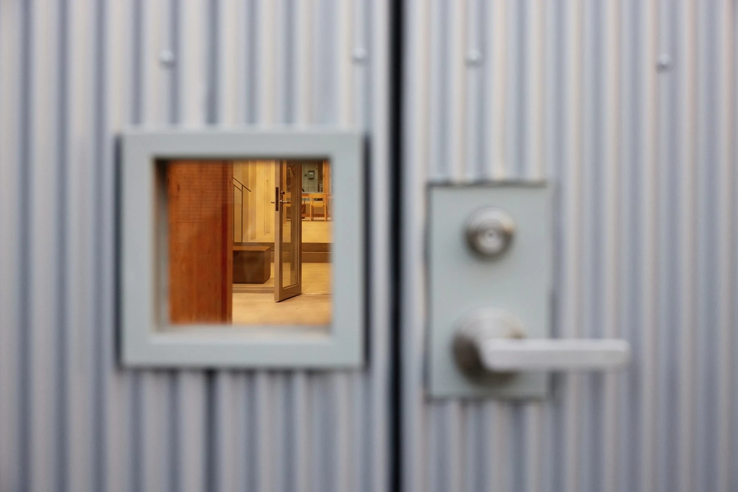 Uchida Shoten Head Office by Jo Nagasaka / Schemata Architects — A diagonal grid of hinged metal awning windows punctuates the white corrugated metal facade, their outward swing mechanism visible as dark lines across the...