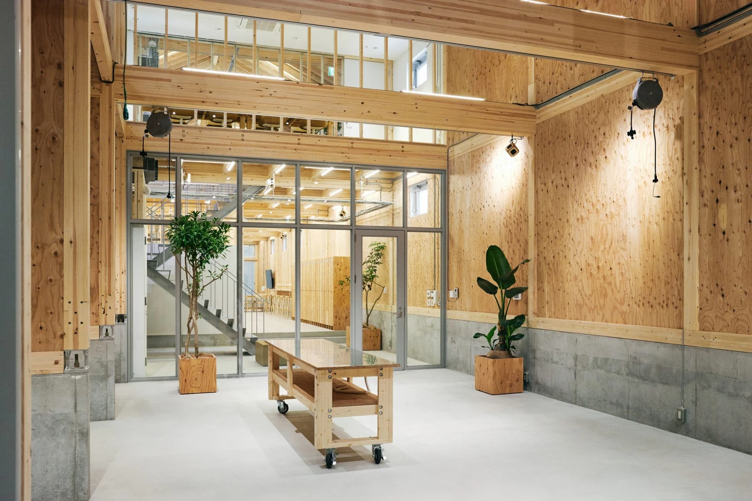 Uchida Shoten Head Office by Jo Nagasaka / Schemata Architects — Interior view of a timber-framed workspace with cork-clad walls and a white polished concrete floor.