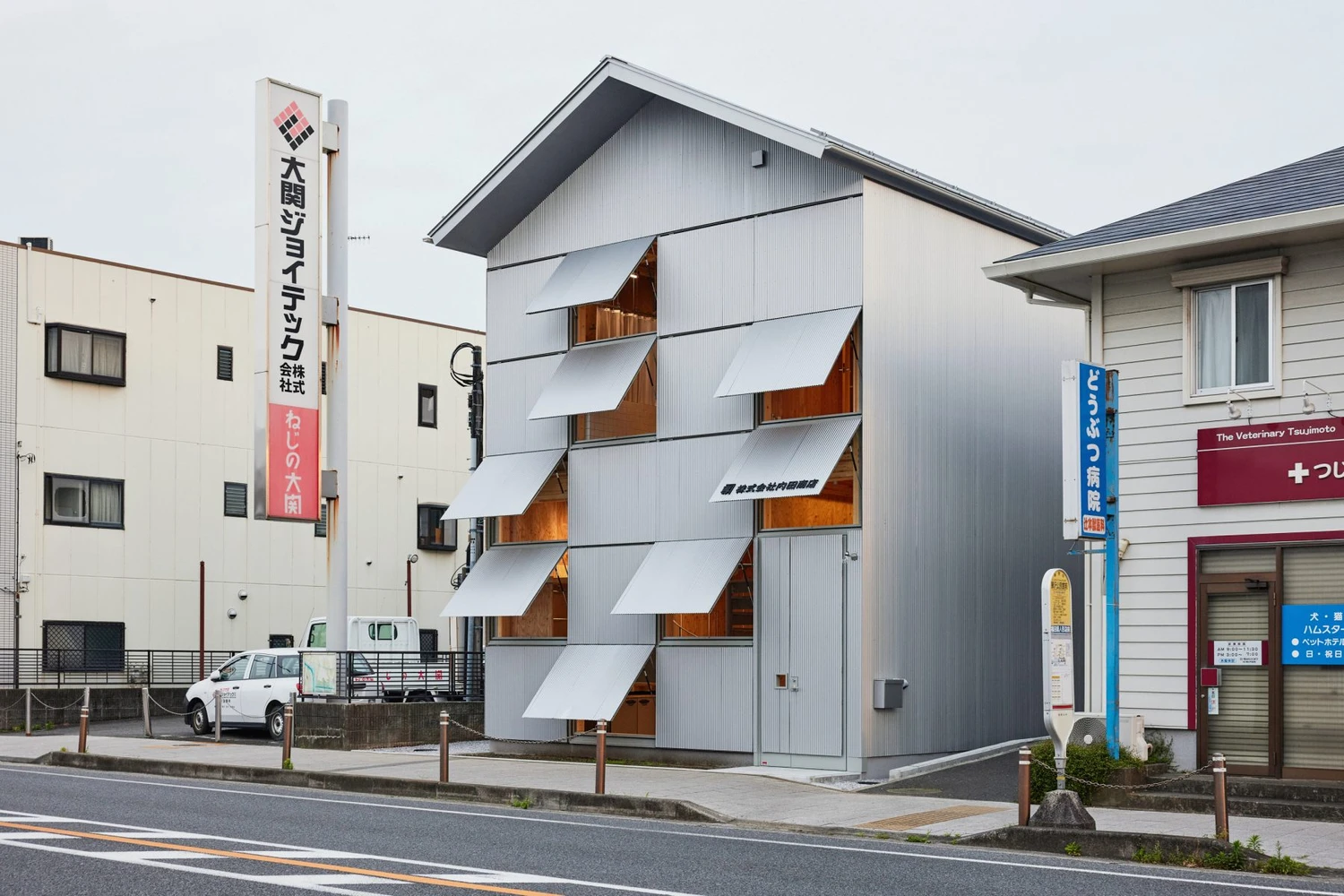 Uchida Shoten Head Office by Jo Nagasaka / Schemata Architects — A four-story infill structure on Fujisawa's historic Tōkaidō corridor employs a diagonal grid of hinged metal awning windows that swing outward across a...