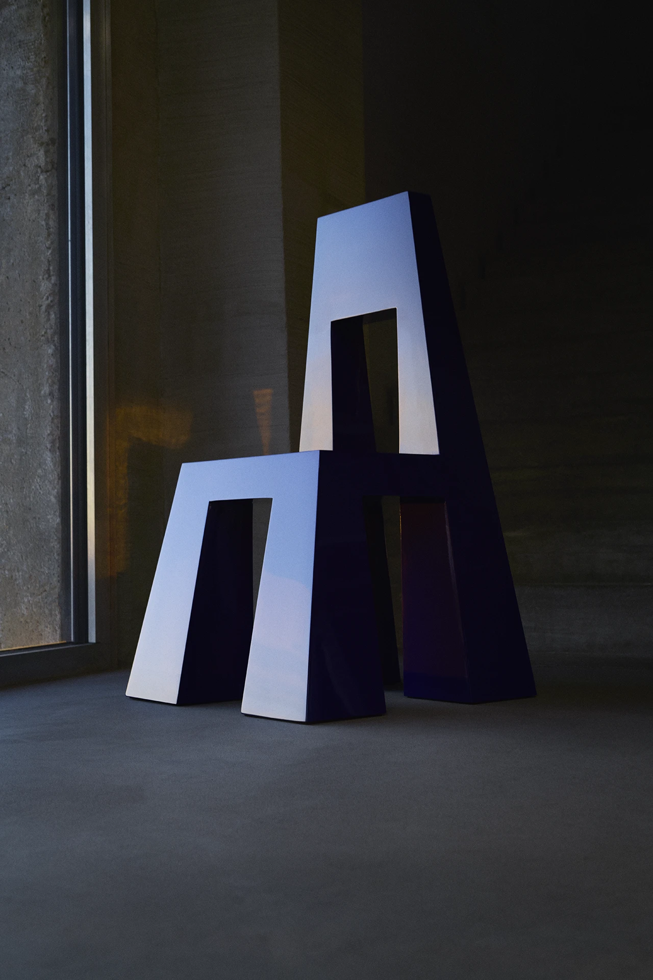 Fermo by Tobias Faisst — Fermo presents two stacked trapezoidal forms in saturated ultramarine blue, each punctuated by a rectangular void that reveals a black metal frame beneath.